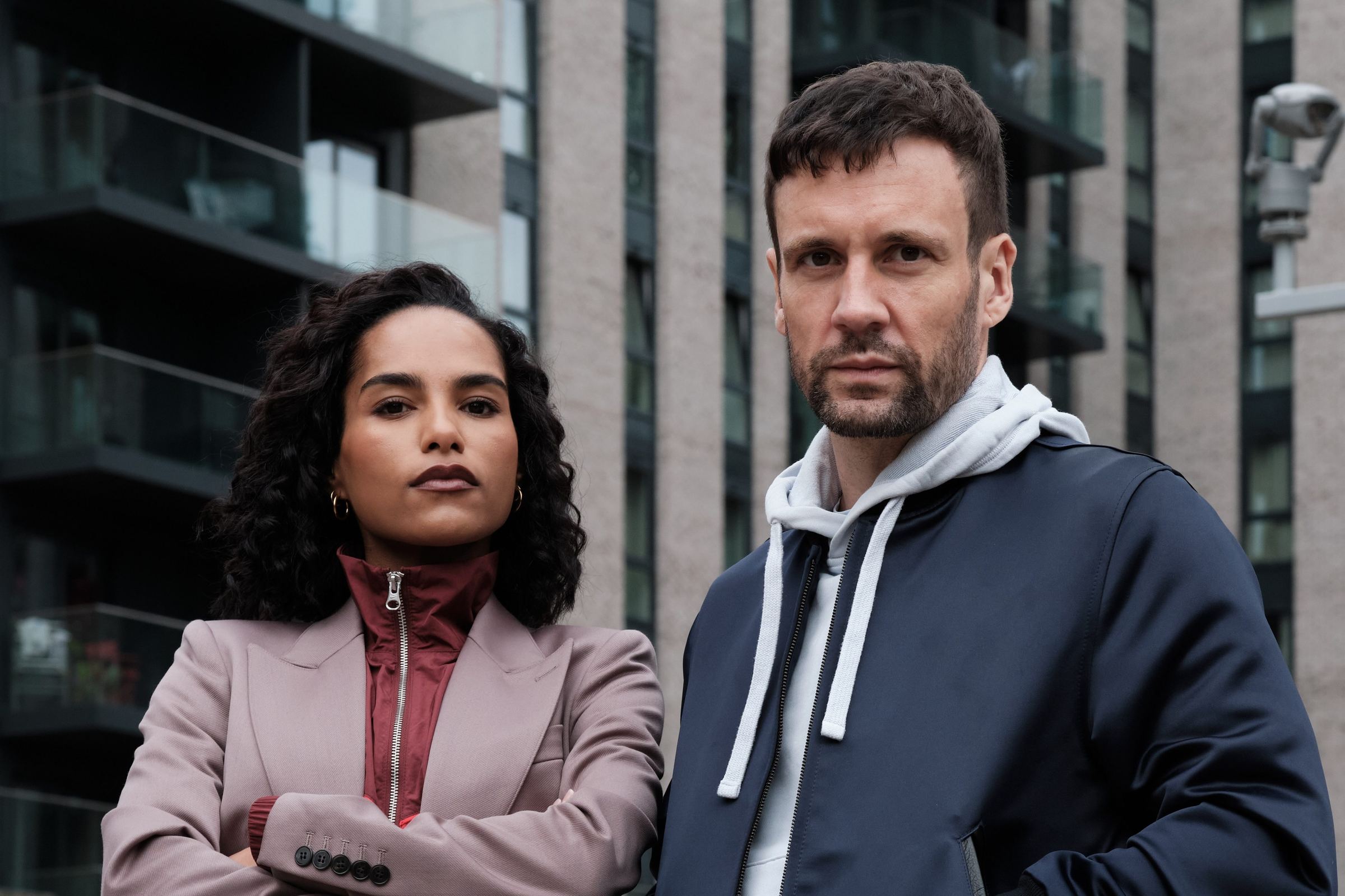 Hitpoint: the two leads stand side by side in front of a block of flats